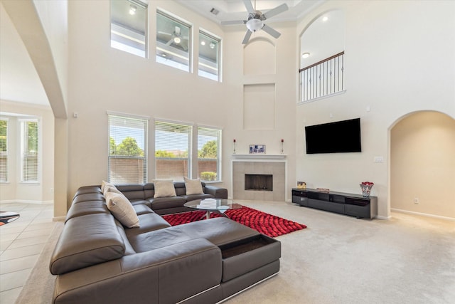 6015 Turner Shadow Ln, Sugar Land, TX 77479 - living area with arched walkways, a towering ceiling, ceiling fan, a tiled fireplace, and baseboards