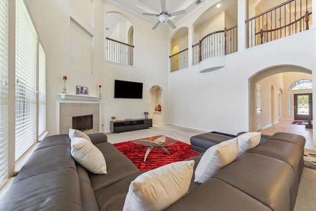 6015 Turner Shadow Ln, Sugar Land, TX 77479 - carpeted living area featuring arched walkways, a high ceiling, a fireplace, a ceiling fan, and baseboards