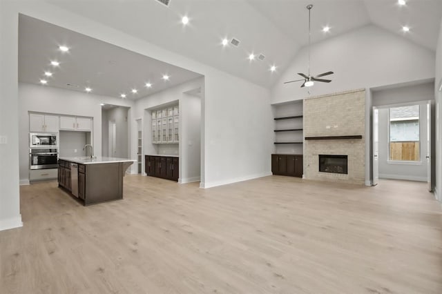 15212 Deseo Dr, Conroe, TX 77302 - unfurnished living room with a sink, a large fireplace, a ceiling fan, light wood-style floors, and baseboards