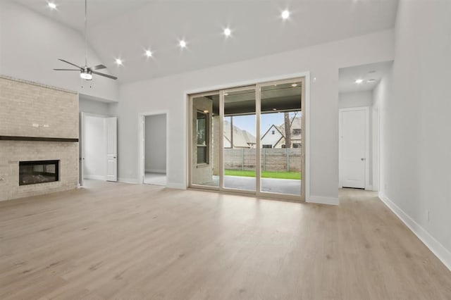 15212 Deseo Dr, Conroe, TX 77302 - unfurnished living room featuring light wood-style flooring, baseboards, a fireplace, a ceiling fan, and lofted ceiling