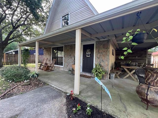 880 E Tram Rd, Vidor, TX 77662 - property entrance with stone siding, fence, and a porch