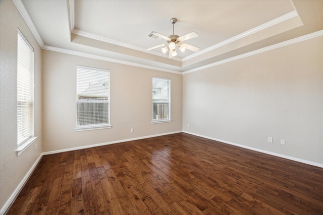 empty room with a raised ceiling, plenty of natural light, crown molding, dark wood-style floors, and ceiling fan