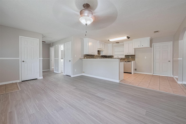 210 N Shirley Ln, Willis, TX 77378 - kitchen featuring dishwasher, white cabinets, light wood finished floors, a textured ceiling, and baseboards