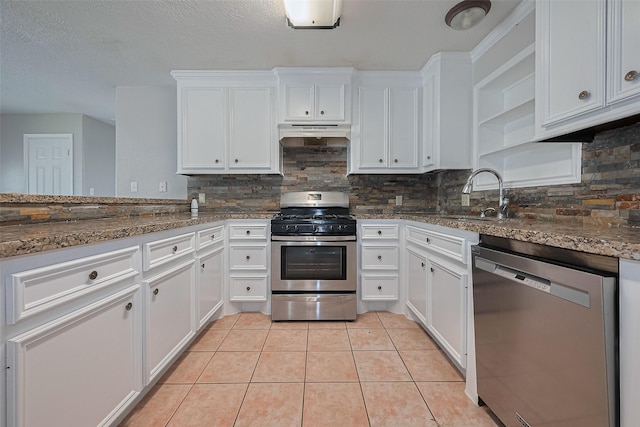 210 N Shirley Ln, Willis, TX 77378 - kitchen with appliances with stainless steel finishes, a sink, under cabinet range hood, white cabinets, and tasteful backsplash