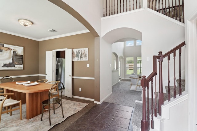 5023 Royal Arbor Ln, Houston, TX 77084 - dining area with dark tile patterned floors, arched walkways, a high ceiling, stairs, and ornamental molding