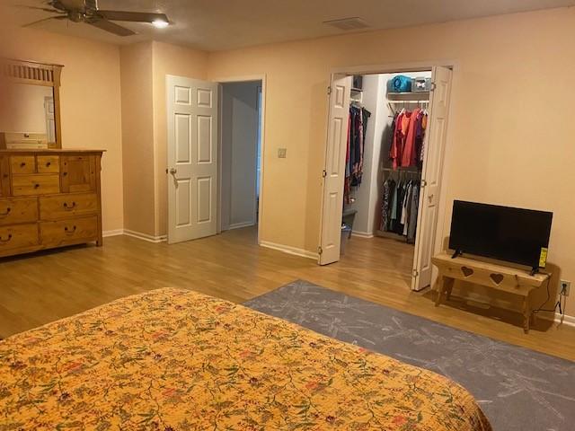 21626 Gentry Rd, Cypress, TX 77429 - bedroom with wood finished floors, a walk in closet, baseboards, and a closet