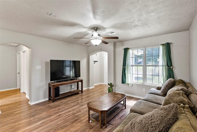 1160 Cottage Grove Cir, Bryan, TX 77801 - living room with arched walkways, wood finished floors, a ceiling fan, a textured ceiling, and baseboards