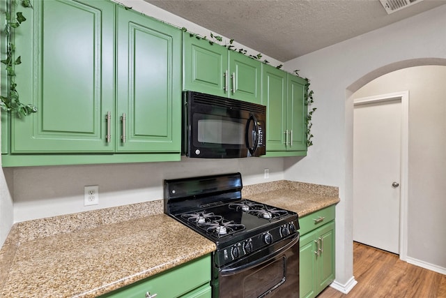 1160 Cottage Grove Cir, Bryan, TX 77801 - kitchen with black appliances, arched walkways, light countertops, light wood-style floors, and green cabinets