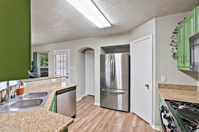 1160 Cottage Grove Cir, Bryan, TX 77801 - kitchen with appliances with stainless steel finishes, green cabinetry, a sink, a textured ceiling, and arched walkways