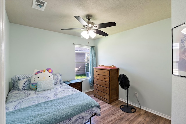 1160 Cottage Grove Cir, Bryan, TX 77801 - bedroom with wood finished floors, baseboards, a textured ceiling, and a ceiling fan