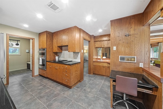 1710 Magnolia Ln, Kingwood, TX 77339 - kitchen featuring double oven, brown cabinets, dark countertops, backsplash, and cooktop