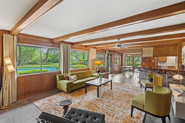 1710 Magnolia Ln, Kingwood, TX 77339 - living area featuring wooden walls, tile patterned floors, beam ceiling, and ceiling fan