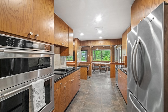 1710 Magnolia Ln, Kingwood, TX 77339 - kitchen with stainless steel appliances, dark countertops, brown cabinets, decorative backsplash, and wooden walls