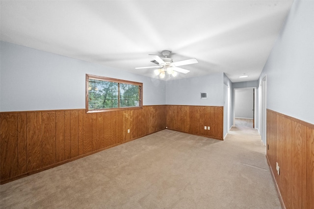 1710 Magnolia Ln, Kingwood, TX 77339 - spare room with wainscoting, wood walls, a ceiling fan, and light carpet