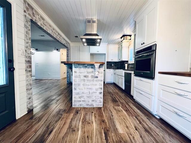 225 Lexington Dr, Vidor, TX 77662 - kitchen with black appliances, exhaust hood, white cabinets, dark wood-style floors, and wood ceiling