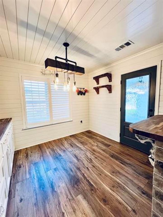 225 Lexington Dr, Vidor, TX 77662 - unfurnished dining area featuring plenty of natural light, dark wood-style floors, crown molding, and wooden walls