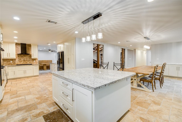 4438 Wigton Dr, Houston, TX 77096 - kitchen featuring stone tile flooring, wall chimney range hood, freestanding refrigerator, tasteful backsplash, and a center island