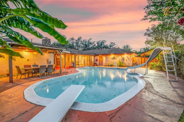 4438 Wigton Dr, Houston, TX 77096 - pool at dusk featuring a water slide, a diving board, a patio area, and fence