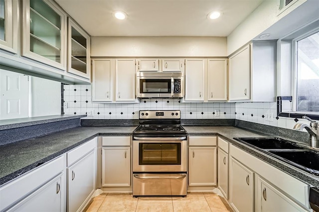 4747 Nasa Pkwy Unit 104, Pasadena, TX 77586 - kitchen with appliances with stainless steel finishes, a sink, decorative backsplash, glass insert cabinets, and recessed lighting
