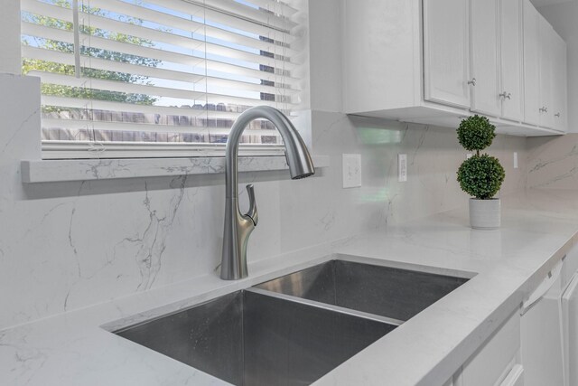 7918 Swan Ln, Baytown, TX 77523 - detailed view of a sink, backsplash, white cabinets, and light stone counters