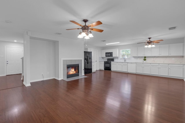 7918 Swan Ln, Baytown, TX 77523 - unfurnished living room with a ceiling fan, dark wood-style flooring, a sink, a tile fireplace, and baseboards