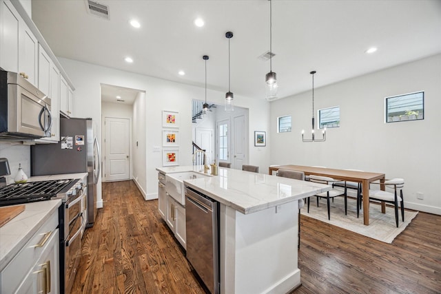 kitchen featuring appliances with stainless steel finishes, a sink, white cabinets, dark wood finished floors, and an island with sink