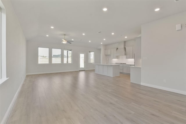 13140 Soaring Forest Dr, Conroe, TX 77302 - unfurnished living room with light wood finished floors, baseboards, recessed lighting, a ceiling fan, and a sink