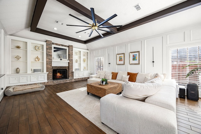 16019 Mickleham Dr, Spring, TX 77379 - living area with a ceiling fan, dark wood-style flooring, a brick fireplace, beam ceiling, and built in features