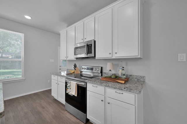 9040 Pecos Pl, Willis, TX 77378 - kitchen featuring appliances with stainless steel finishes, dark wood-type flooring, healthy amount of natural light, white cabinetry, and recessed lighting