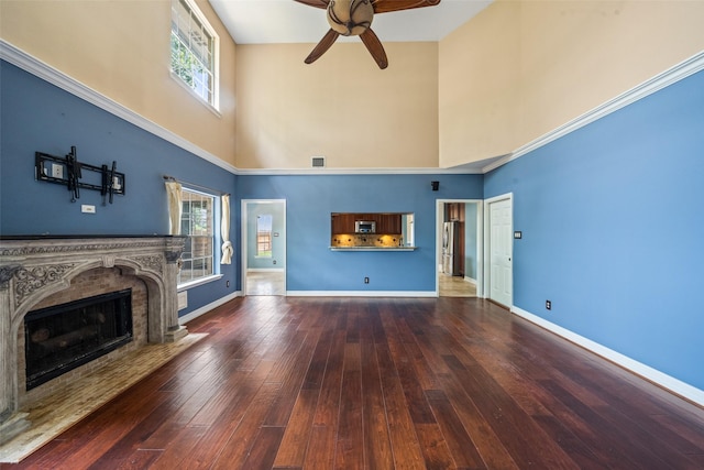 2502 Sea Horse Ct, Seabrook, TX 77586 - unfurnished living room with a towering ceiling, ceiling fan, hardwood / wood-style flooring, a premium fireplace, and baseboards