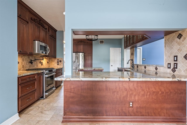 2502 Sea Horse Ct, Seabrook, TX 77586 - kitchen featuring stainless steel appliances, backsplash, light stone counters, and a peninsula