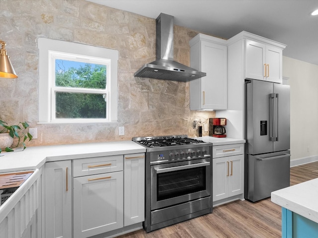 8253 Carolyn St, Santa Fe, TX 77517 - kitchen with stainless steel appliances, wall chimney exhaust hood, light wood-style floors, and light countertops