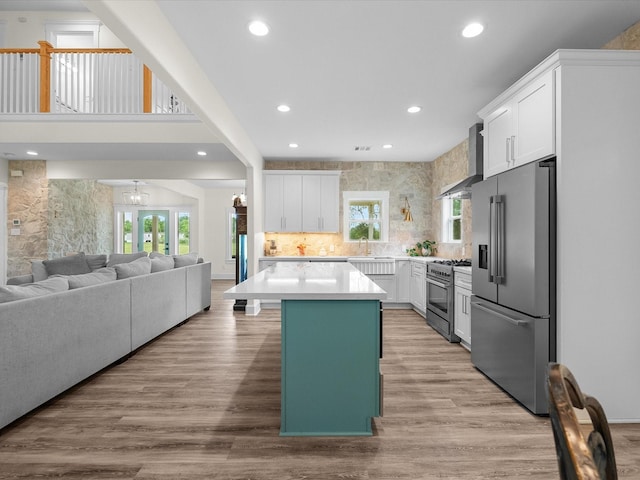 8253 Carolyn St, Santa Fe, TX 77517 - kitchen with premium appliances, wall chimney range hood, open floor plan, recessed lighting, and white cabinets