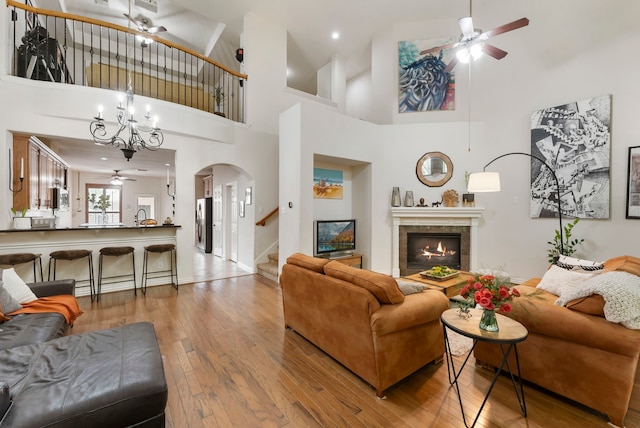 27 Medley Ln, The Woodlands, TX 77382 - living room with a ceiling fan, arched walkways, a tiled fireplace, wood-type flooring, and stairway
