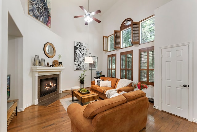 27 Medley Ln, The Woodlands, TX 77382 - living room featuring hardwood / wood-style flooring, a tile fireplace, a towering ceiling, and a ceiling fan