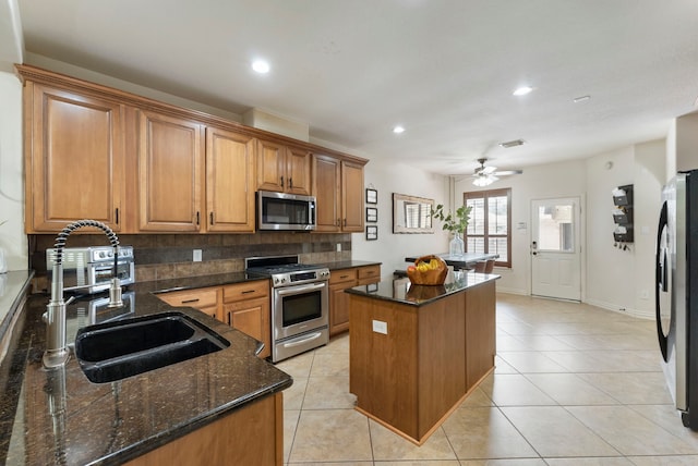 27 Medley Ln, The Woodlands, TX 77382 - kitchen with appliances with stainless steel finishes, a center island, backsplash, brown cabinets, and a ceiling fan