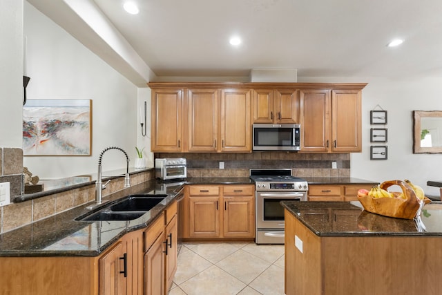 27 Medley Ln, The Woodlands, TX 77382 - kitchen with stainless steel appliances, decorative backsplash, dark stone countertops, light tile patterned flooring, and brown cabinets
