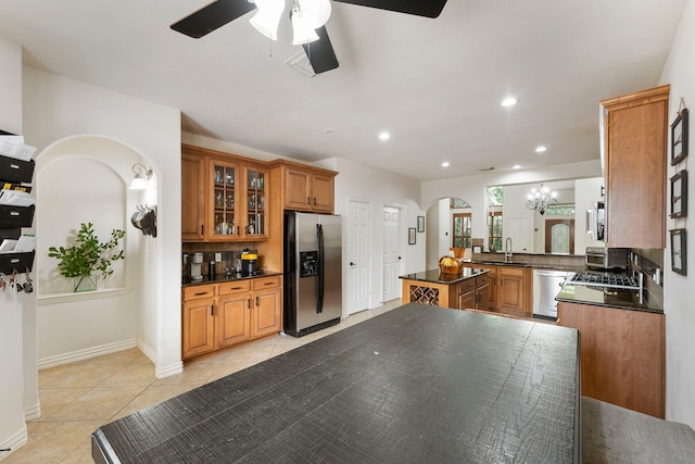 27 Medley Ln, The Woodlands, TX 77382 - kitchen featuring appliances with stainless steel finishes, dark countertops, ceiling fan, brown cabinetry, and arched walkways