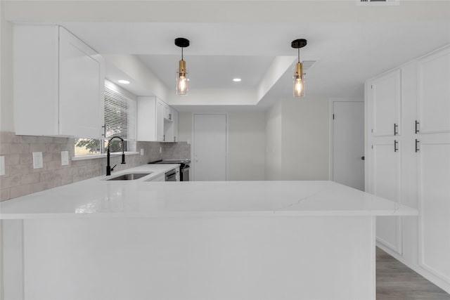 18010 Santolina Ln, Katy, TX 77449 - kitchen featuring a sink, tasteful backsplash, a peninsula, white cabinetry, and light wood-style floors