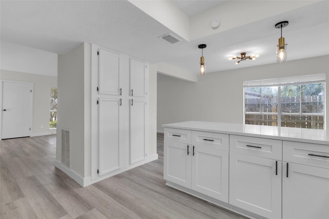 18010 Santolina Ln, Katy, TX 77449 - kitchen featuring light wood-style flooring, white cabinets, pendant lighting, and light countertops
