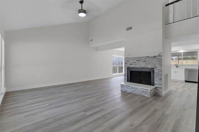18010 Santolina Ln, Katy, TX 77449 - unfurnished living room featuring a ceiling fan, healthy amount of natural light, a towering ceiling, light wood-type flooring, and a stone fireplace