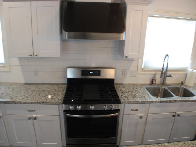 2405 Keene St, Houston, TX 77009 - kitchen featuring ventilation hood, stainless steel gas stove, a sink, white cabinetry, and decorative backsplash
