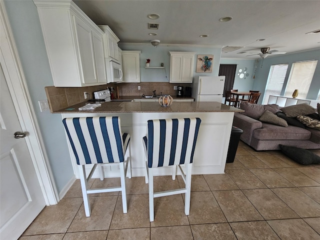 970 Olive Dr, Crystal Beach, TX 77650 - kitchen featuring white appliances, white cabinetry, a ceiling fan, decorative backsplash, and recessed lighting