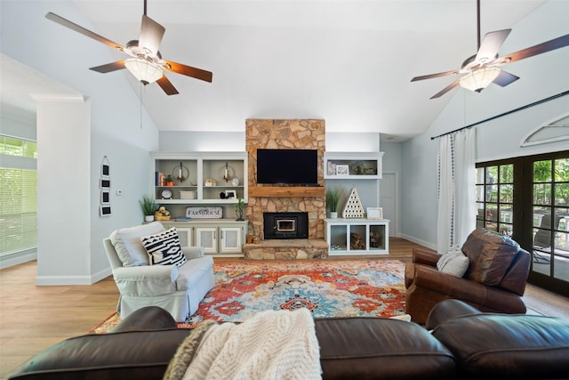 living room with a ceiling fan, high vaulted ceiling, baseboards, light wood-style flooring, and a fireplace