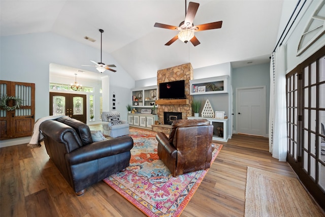 living room featuring ceiling fan, a stone fireplace, lofted ceiling, wood finished floors, and french doors
