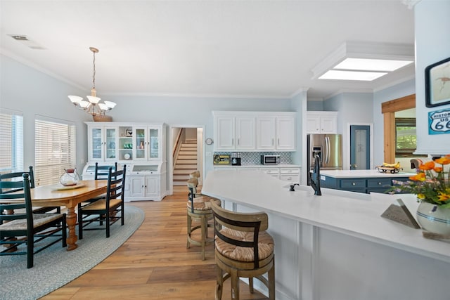 kitchen featuring a chandelier, stainless steel fridge, light wood-style floors, crown molding, and light countertops