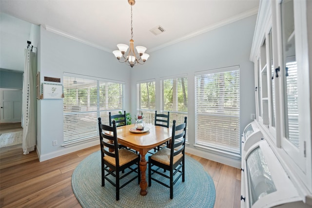 dining space featuring crown molding, a chandelier, baseboards, and wood finished floors