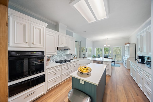 kitchen with appliances with stainless steel finishes, a peninsula, a warming drawer, tasteful backsplash, and light countertops