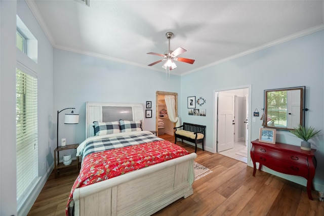 bedroom featuring wood finished floors, crown molding, baseboards, and a ceiling fan