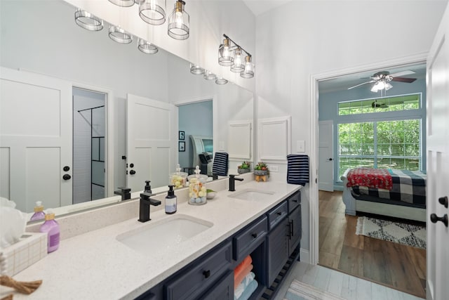 ensuite bathroom with double vanity, a ceiling fan, and wood finished floors